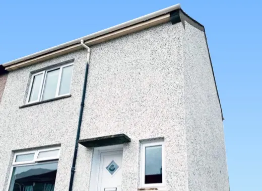 Roughcast finish on a house corner and gutter detail
